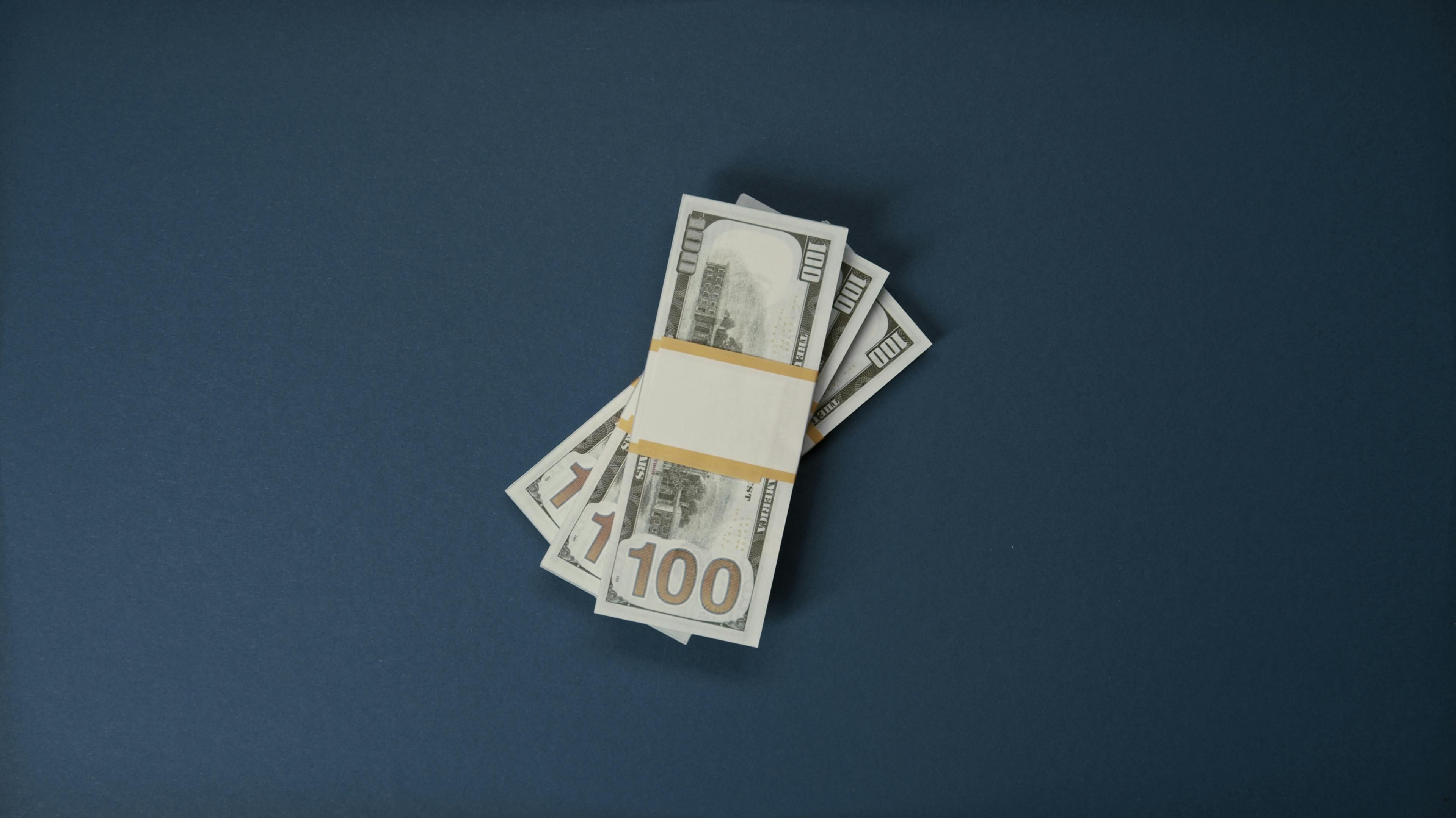 100 Dollar Bills on Blue Surface